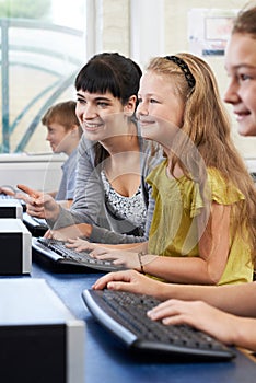 Female Elementary Pupil In Computer Class With Teacher