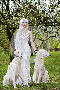 Female Elf with Long White Hair Holding A Pair of Greyhounds in Forest Outdoors.Posing Against Sunglight