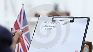 Female embassy worker checking United Kingdom visa application, marking denied