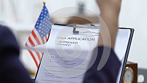 Female embassy worker checking US visa application, marking approved, permission