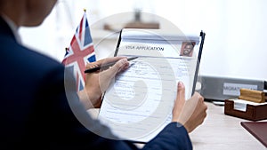 Female embassy worker checking visa application office, british flag, migration