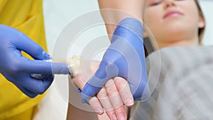 A female employee of a beauty salon waxes the body of a young beautiful girl. Painless hair removal