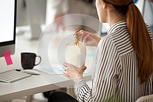 Female employee eating Asian noodles during office work break