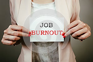 Female employee holding note with text job burnout. Leave employment, overworking, quitting work concept