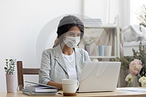 Female employee in medical mask working in office