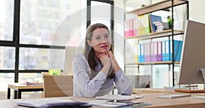 Female employee of successful corporation sits at desk