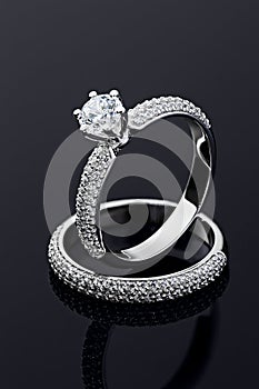 Female engagement and wedding rings with diamonds on black background