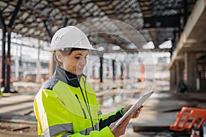 Female engineer checking building documentation on clipboard at construction site.