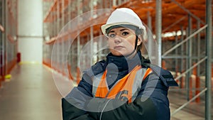 Female engineer with crossed arms stands against empty racks