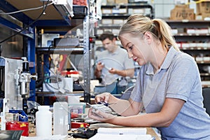 Female Engineer In Factory Measuring Component At Work Bench Using Micrometer