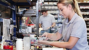 Female engineer in factory measuring component at work bench using micrometer