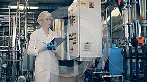 Female engineer, factory worker checks machines at a modern plant, factory. Female worker controls the quality of
