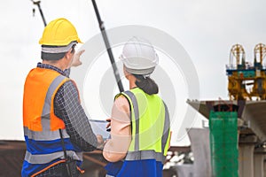 Female engineer and foreman worker checking project at building site, Engineer and builders in hardhats discussing on construction