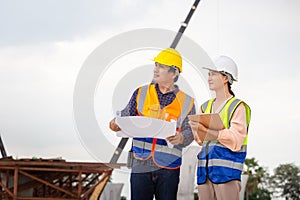 Female engineer and foreman worker checking project at building site, Engineer and builders in hardhats discussing on construction