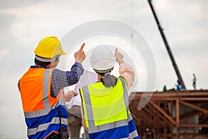 Female engineer and foreman worker checking project at building site, Engineer and builders in hardhats discussing on construction