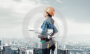 Female engineer in hardhat standing with blueprint