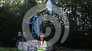 Female engineer holds tablet in hands and makes calculations for oil production