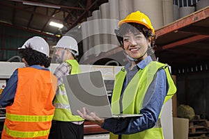 Female engineer with laptop happy smile at a machine in paper industry factory