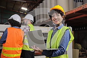 Female engineer with laptop happy smile at a machine in paper industry factory