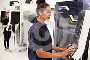 Female Engineer Operating CNC Machinery On Factory Floor