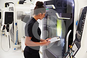 Female Engineer Operating CNC Machinery On Factory Floor