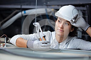 female engineer in roofspace holding pliers