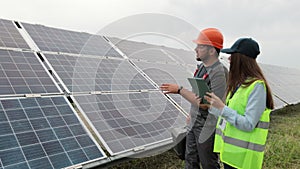 Female engineer specialist and man electrical worker walking on photovoltaic solar panels and discussing future plans