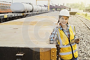 Female engineer standing with laptop outside a maintenance train station smiling at the camera.