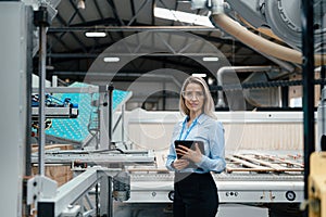 Female engineer standing in modern industrial factory. Manufacturing facility with robotics and automation. Female