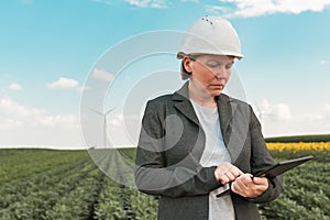 Female engineer with tablet computer on modern wind turbine farm