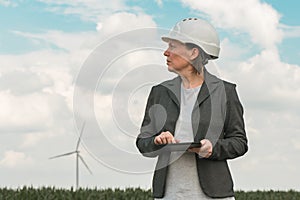 Female engineer with tablet computer on modern wind turbine farm