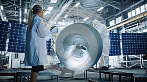 Female Engineer Uses Digital Tablet Computer while Working on Satellite Construction. Aerospace