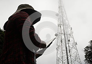 Female engineer using tablet computer checking the frequency with telecommunication towers with TV antennas and satellite dish In