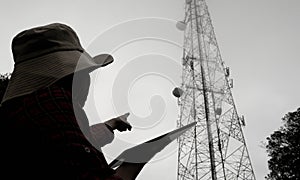 Female engineer using tablet computer checking the frequency with telecommunication towers with TV antennas and satellite dish In