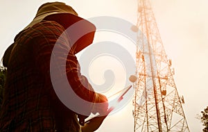 Female engineer using tablet computer checking the frequency with telecommunication towers with TV antennas and satellite dish In