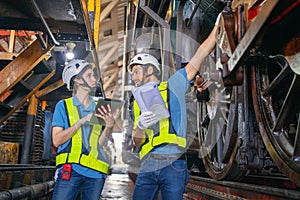 Female engineer and worker checking equipment in factory for repair