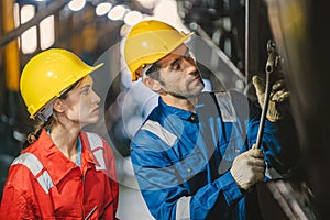 Female engineer and worker checking equipment in factory for repair