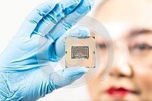 A female engineer working in a lab wearing protective goggles and gloves holds the new processor in her hands and examines it.