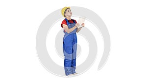 Female engineer in yellow safety helmet is looking to tablet computer while checking for construction building on white