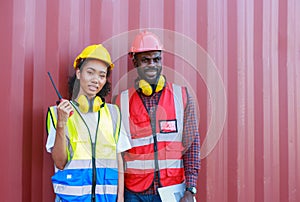 A female engineer and a young African-American man monitor and supervises the loading of containers at a commercial shipping port