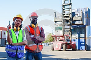 A female engineer and a young African-American man monitor and supervises the loading of containers at a commercial shipping port