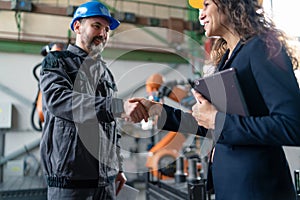 Female engineering manager and mechanic worker fist bumping in industrial factory