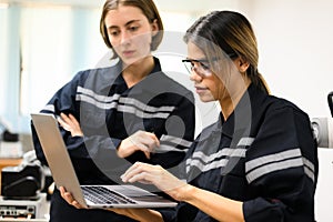 Female engineers using laptop checking and operating robotic machine