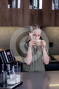 Female enjoying of fresh coffee aroma after brewing coffee using coffee maker in the kitchen at home