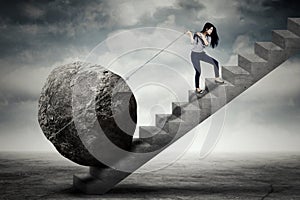 Female entrepreneur carrying big stone on the stair photo