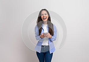 Female entrepreneur laughing and scrolling social media on smart phone against white background