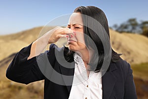 Female entrepreneur making bad smell gesture holding nose