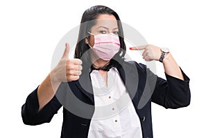 Female entrepreneur pointing at mask making thumb up gesture