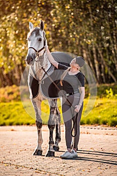 Female equestrian horse rider patting her gray horse