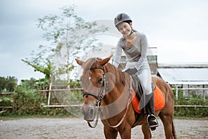 Female equestrian smiling while riding horse and holding reins